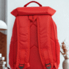 Bright red waterproof backpack with flap top buckle closure and side mesh pockets against a neutral background.